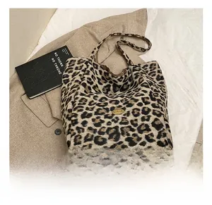 Close-up of leopard print plush bucket bag with golden logo and brown leather handle