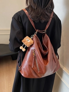 Brown vintage faux leather backpack with plush bear charm shown in a rear view lifestyle shot