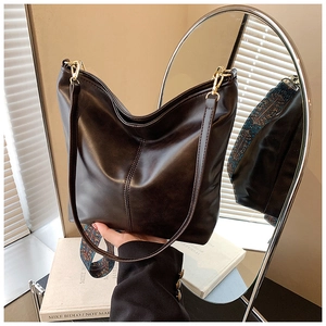Detail view of large brown bucket bag with bohemian strap and matte leather finish