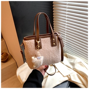 Detail of beige faux shearling bucket bag with dark brown leather handles and monster charm