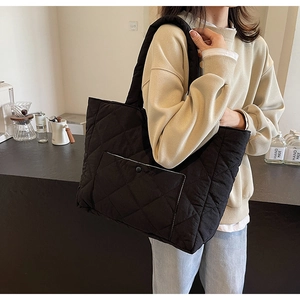 Detail view of black quilted tote bag with side pocket and snap button on a model