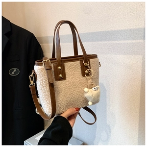 Detail of plush lambskin bucket bag featuring brown leather trim and cute monster charm