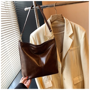 Detailed view of dark brown leather tote bag with gold metal hooks and stitch accents