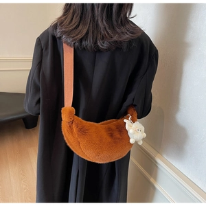 Brown faux fur crescent crossbody bag with orange strap and sheep pendant on model