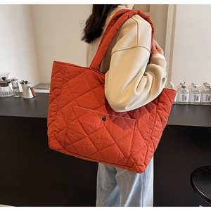 Close-up of diamond quilted tote bag featuring a front pocket with metal button