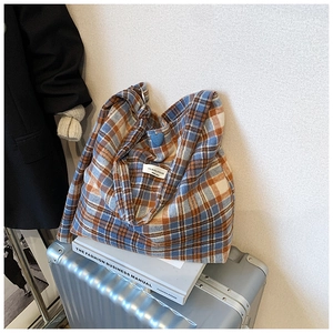 Détail du cabas à carreaux avec breloque cœur sur valise métallique et livres de mode