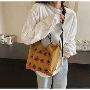 Detail der braunen Canvas-Tasche mit Kirschstickerei und gestreiftem Seilschultergurt