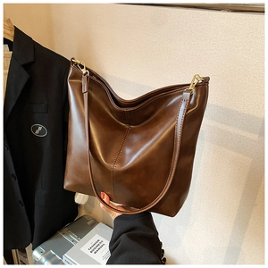 Brown leather tote bag detail with gold hardware and shoulder strap in business setting