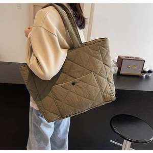 Detail of olive green quilted tote bag showing diamond stitch pattern and front pocket