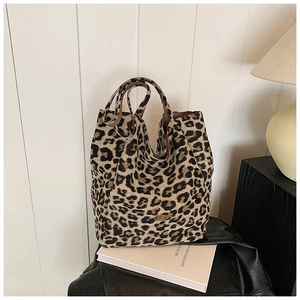 Close-up of leopard print tote bag fabric with oval decorative plaque and dual handles