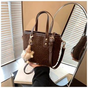 Close-up of small brown teddy plush bucket bag with leather handle and cute bear charm