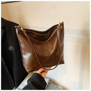Detail of dark brown leather bucket bag with V-shaped stitching and gold hardware hooks