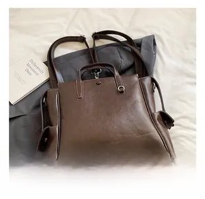 Detail of dark brown leather backpack showing reinforced handles and magnetic side pocket