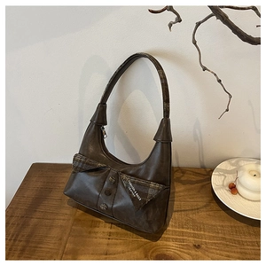 Detail of retro brown leather hobo bag with large plaid bow and decorative buttons
