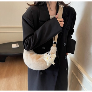 Detail of soft beige plush crescent bag with cute sheep charm on model wearing black blazer