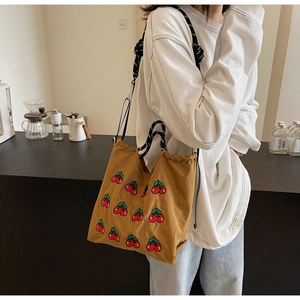 Detail einer braunen Canvas-Tasche mit Kirschstickerei und Baumwollseil-Schultergurten