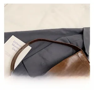 Detail of soft brown leather tote handle on blue blazer background with minimalist props