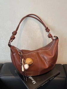 Brown semi-circle crossbody bag with contrast stitching and baseball pendant charm