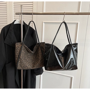 Détail de sacs cabas à imprimé léopard et en similicuir noir brillant sur support