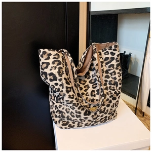 Close-up of leopard print tote bag detailing golden metal plaque and textured fabric