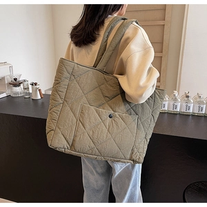 Detail of olive green quilted tote bag with diamond stitching and snap button pocket