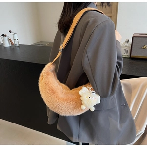 Detail of camel plush crescent bag with fuzzy monster charm and wide strap