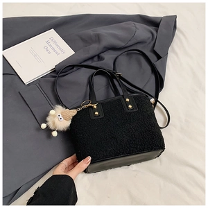 Detail of black fuzzy bucket bag with plush toy pendant and golden metal studs