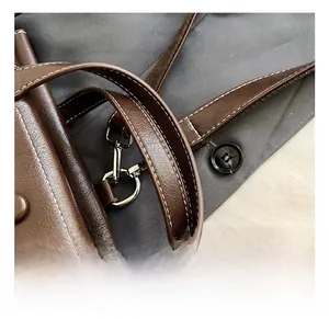 Detail of brown leather bag handle with contrast stitching and metallic strap hooks
