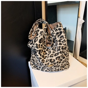 Detail of leopard print tote bag featuring a gold handmade metal plate on plush fabric
