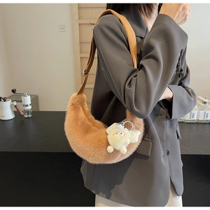 Caramel faux fur crescent shoulder bag with white pompom worn over a grey blazer
