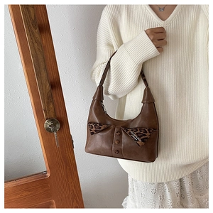 Detail of vintage dark brown shoulder bag with leopard print bow and button accents