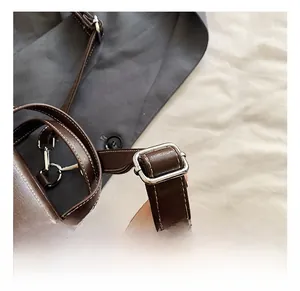 Detail of dark brown leather strap with white stitching and silver metal adjustment buckle