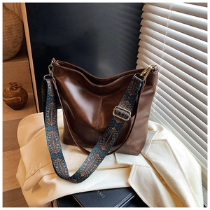 Close-up of a brown tote bag with vintage jacquard strap and gold metal buckles