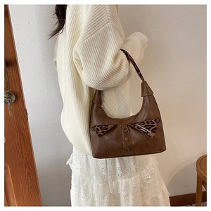 Close-up of retro brown shoulder bag featuring leopard print flap and decorative buttons