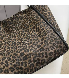 Détail du cabas tissé à motif léopard montrant la texture et le liseré en cuir noir