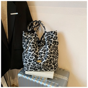Detailed view of plush leopard print tote bag with a golden handmade metal label