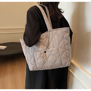 Detail showing light gray quilted tote bag with front pocket and snap button closure