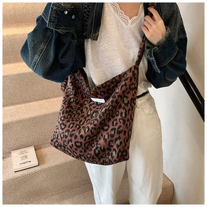 Détail du sac cabas en tricot léopard avec bouton décoratif et étiquette tissée