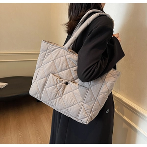 Detail of grey quilted tote bag featuring a large diamond pattern and snap pocket