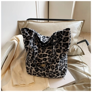 Close-up of leopard print plush bucket bag with handmade metal tag on a leather chair