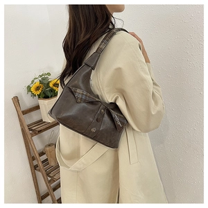 Close-up of a vintage dark brown shoulder bag with textured flap and fashion lettering