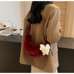 Detail of burgundy plush crescent bag with a cute bow charm in a cozy cafe setting