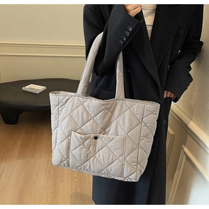 Close-up of light grey quilted tote bag with front pocket and elegant square stitching