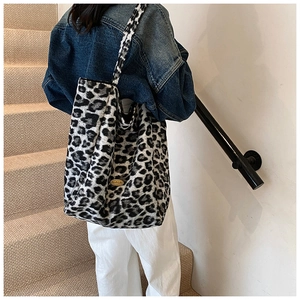Detail showing plush leopard print tote bag with handmade gold metal plate