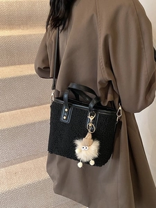 Black faux fur bucket bag for women with leather handles and a plush monster charm