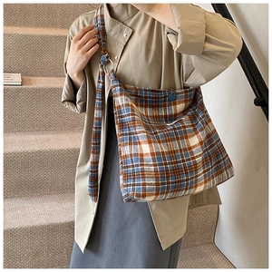 Détail d'un grand sac cabas à carreaux avec large bandoulière et écusson cœur bleu