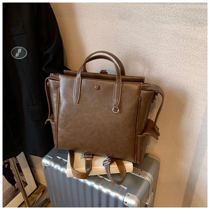 Detail view of brown vintage leather backpack with contrast stitching on a suitcase