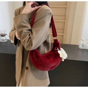 Detail of burgundy plush crescent bag with wide shoulder strap and bear charm
