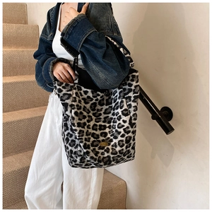 Detail of plush leopard print bucket bag featuring soft texture and metal logo plaque