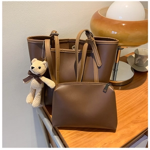 Detailed view of brown leather tote bag with matching zipper pouch and knit bear charm